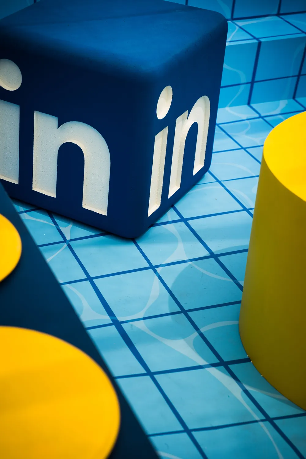Giant blue LinkedIn cubes on a tiled pool deck with yellow accents