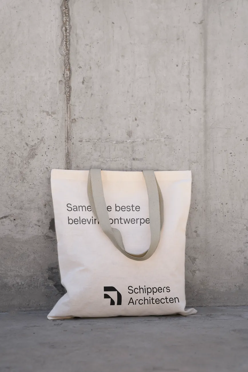 Tote bag with Samen de beste beleving ontwerpen against a concrete wall