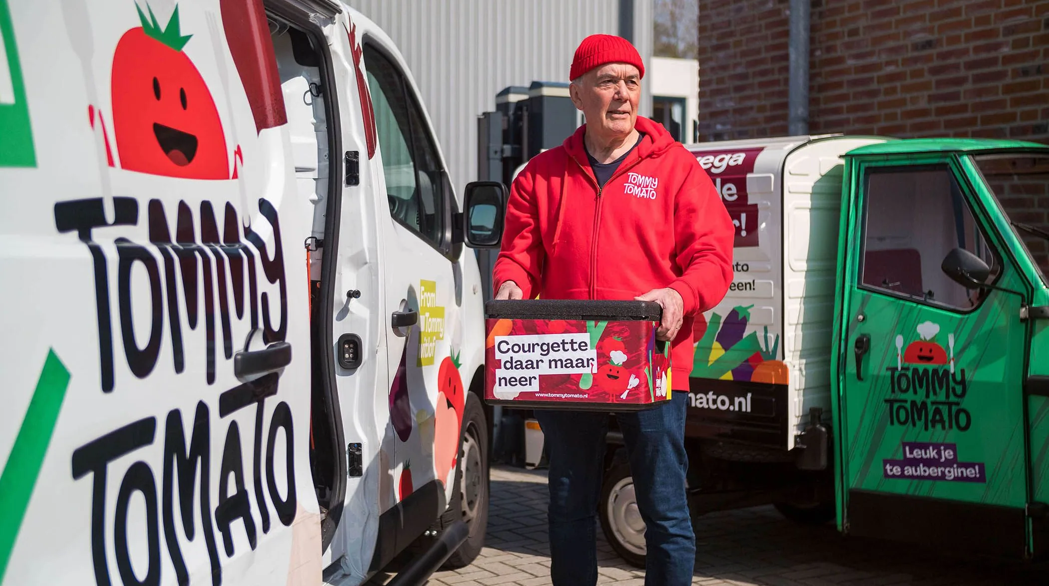 Founder with a lunch box between the branded vans